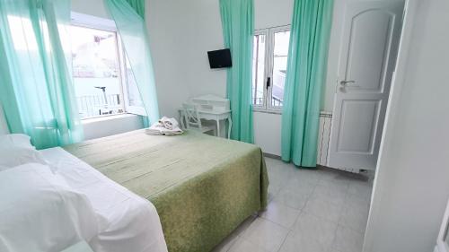 a bedroom with a bed with green curtains and a window at Hotel Casa Nicola in Ischia