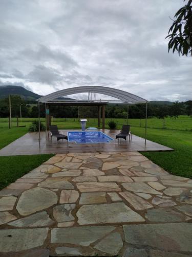 um gazebo com 2 cadeiras e um pátio de pedra em Chácara recanto Feliz em Pirenópolis