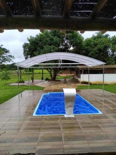 a large white umbrella over a swimming pool at Chácara recanto Feliz in Pirenópolis