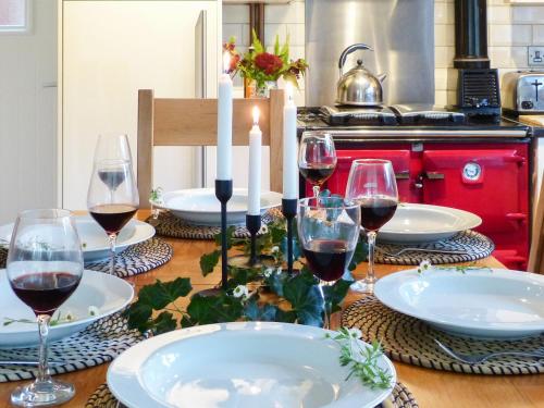 a table with glasses of wine and candles on it at Wildwood Cottage in Germansweek