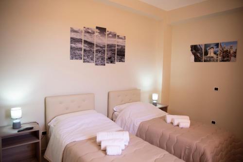 two beds in a room with white sheets at B&B La Terrazza Degli Scrittori in Racalmuto