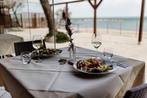 a table with two plates of food and wine glasses at Camping La Pineta in Porto Recanati