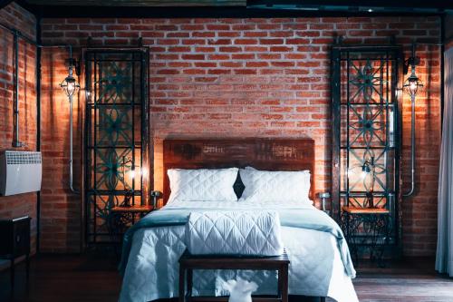 a bedroom with a bed and a brick wall at LA PIANTA - Uma experiência na Villa de Monte Verde in Monte Verde