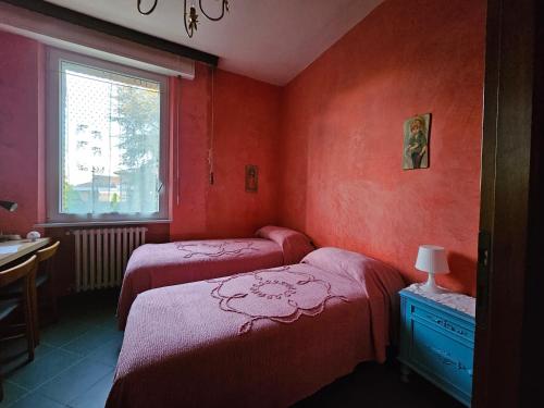 2 Betten in einem Zimmer mit roten Wänden in der Unterkunft Casa VINCENZO 130 mq con 2 Bagni ed ingresso esclusivo dal giardino in Felino