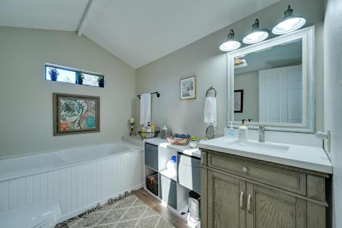 Un baño con bañera, lavabo y espejo. en A-Frame Munds Park Retreat 35 Miles to Snowbowl, en Munds Park