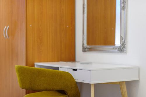 a white desk with a mirror and a yellow chair at Hostel Globo in Šibenik