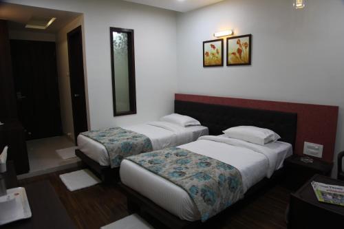 a hotel room with two beds and a mirror at Hotel Pearls in Aurangabad