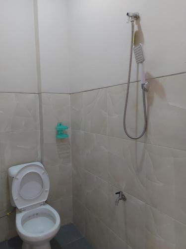 uma casa de banho com um chuveiro e um WC. em GriyaQ Homestay em Kedungwaru