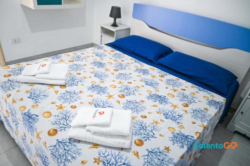 ein Schlafzimmer mit einem blauen und weißen Bett mit Handtüchern in der Unterkunft Appartamenti Jolly by SalentoGo in Torre Lapillo