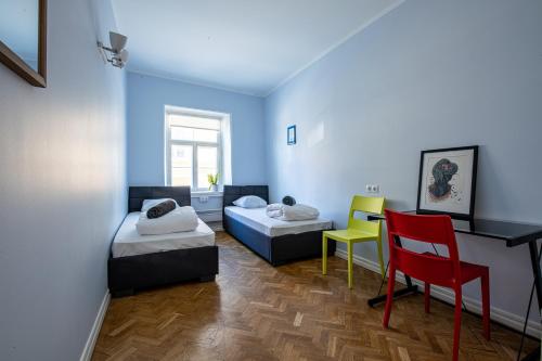 um quarto com duas camas e uma cadeira vermelha em Tallinn Guest House em Talin