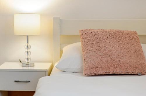 a white bed with a pink pillow on top of it at Hostel Globo in Šibenik