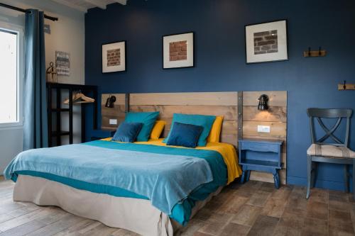 een slaapkamer met een bed met blauwe muren en een stoel bij Les Galapons in Trept