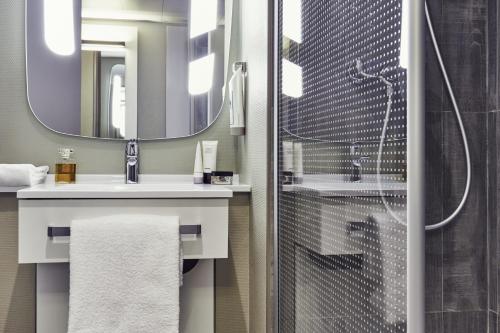 uma casa de banho com um chuveiro, um lavatório e um espelho. em ibis Toulon La Valette em La Valette-du-Var