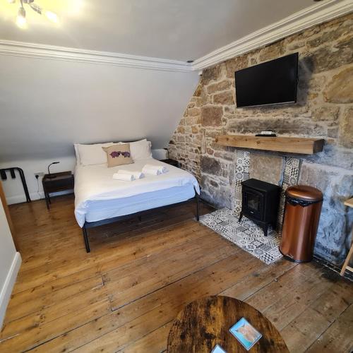 a bedroom with a bed and a fireplace with a television at Ness City Cottage in Inverness