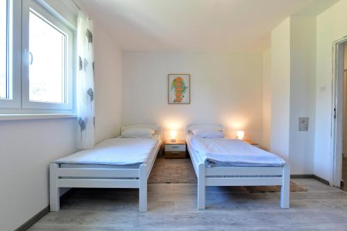 two beds in a room with a window and two lamps at Kuća za odmor Roby in Saborsko