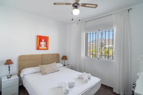 ein weißes Schlafzimmer mit einem Bett und einem Fenster in der Unterkunft Almijara Apartments Casasol in Nerja