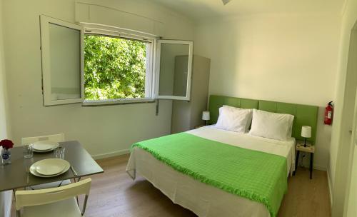 Schlafzimmer mit einem Bett, einem Tisch und einem Fenster in der Unterkunft Ciao Tavira in Tavira