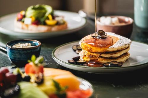 a table topped with plates of pancakes and fruit at Fairmont Château Lake Louise in Lake Louise
