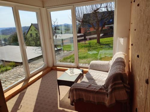 Zimmer mit großen Fenstern, einem Sofa und einem Tisch in der Unterkunft Ferienhaus Rodig Sächsischen Schweiz in Saupsdorf
