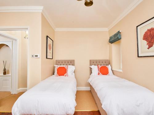 two beds in a room with white and orange pillows at North Lodge in Bakewell