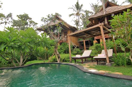 a resort with a swimming pool in front of a house at Jepun Didulu Cottages in Candidasa