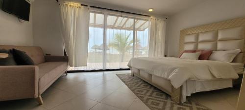 a bedroom with a bed and a couch and a window at Casa Suite Palmar del viento FRENTE, FRENTE AL MAR in Moñitos