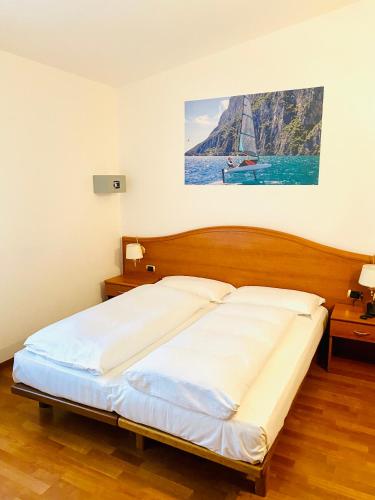 a bed in a bedroom with a painting on the wall at Beach Hotel Rosa in Malcesine