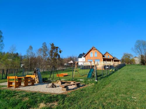 een speeltuin in een veld met een huis op de achtergrond bij Sielski Zakątek Dąbrówka Domki in Dąbrówka