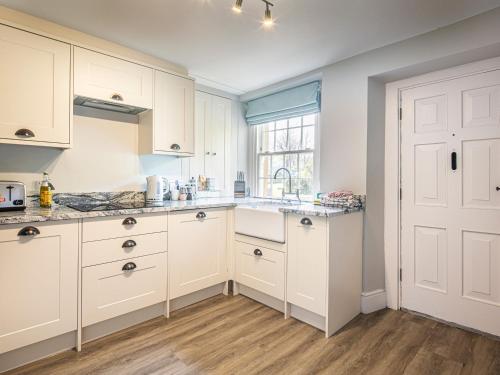 a kitchen with white cabinets and a sink and a window at The Aubrey in Bakewell