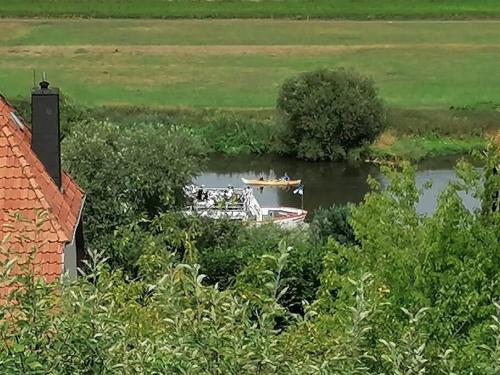 a boat in a river near a house at FeWo mit Weser-Fernblick in Hehlen