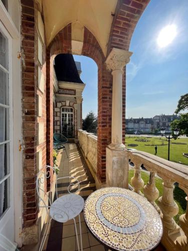a balcony with an archway and a table at La Villa L'Argentine in Cabourg