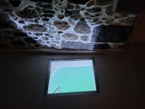 a small window in a room with a stone wall at Spiliani View in Mandrakion