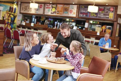 a man and two children sitting at a table eating cake at Sunny Hunny Manor Park Caravan in Hunstanton