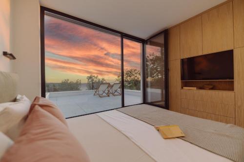 a bedroom with a large window with a sunset view at D-Tree HOUSE private heated pool in Potocnica