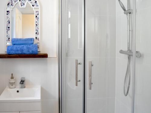 a white bathroom with a shower and a sink at Little Hoot in Baslow