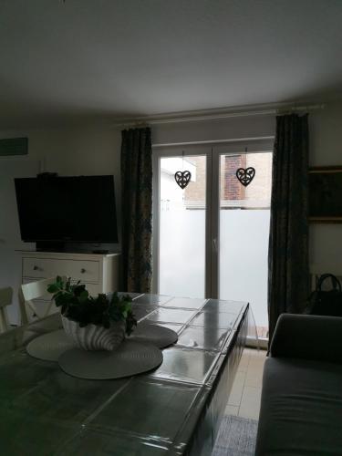 a living room with a glass table and two windows at Hübsches Haus in Emden