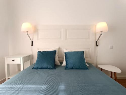 a bed with two blue pillows in a bedroom at 10 MARIA - Faro in Faro