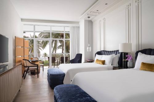 a hotel room with two beds and a living room at The Ritz-Carlton South Beach in Miami Beach