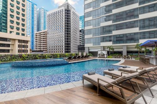 a large swimming pool with lounge chairs and buildings at The Westin Manila in Manila