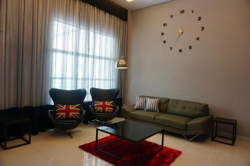 a living room with a couch and two chairs and a clock at Shamrock Boutique Villa - Stay for 12 person in Batu Ferringhi