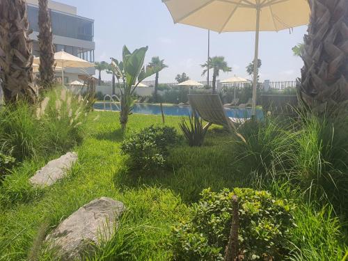 a lawn with a chair and an umbrella and a pool at HEAVEN BEACH in Sidi Rahal