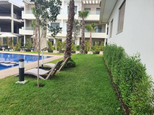 a resort yard with a pool and palm trees at HEAVEN BEACH in Sidi Rahal