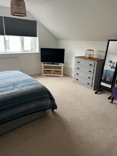ein Schlafzimmer mit einem Bett, einer Kommode und einem TV in der Unterkunft Bescot House Bramble Hill Bude 4 bed det house in Bude