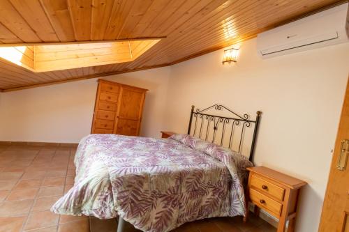 1 dormitorio con cama y techo de madera en Alojamiento Rural Arco Iris, en Arroyo Frío