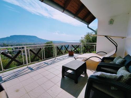 eine Terrasse mit Stühlen und einem Tisch auf dem Balkon in der Unterkunft Délibáb Apartman in Szigliget