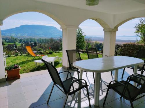 a white table and chairs on a porch with a view at Délibáb Apartman in Szigliget