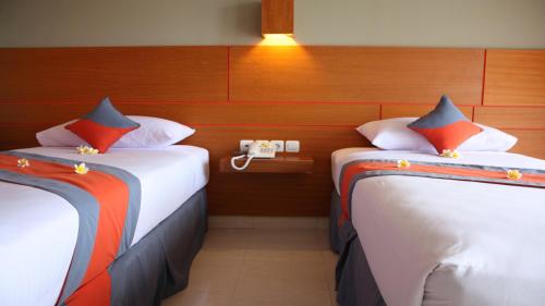 two beds in a room with a phone on the wall at Grand Sinar Indah in Legian