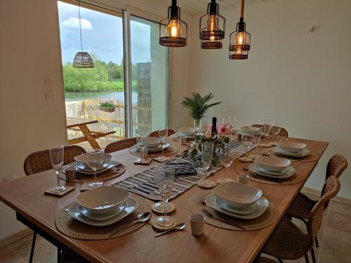 une longue table en bois avec des assiettes et des verres dessus dans l'établissement Détente au bord du Loir - Spa Sauna - Gîte 3, à Les Roches-lʼÉvêque