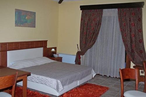 a bedroom with a bed and a table and a window at TSIGOURA VERDE RESORT in Mikros Prinos
