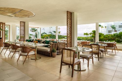 a dining room with tables and chairs and windows at Aurora Anguilla Resort & Golf Club in Ebenezer
